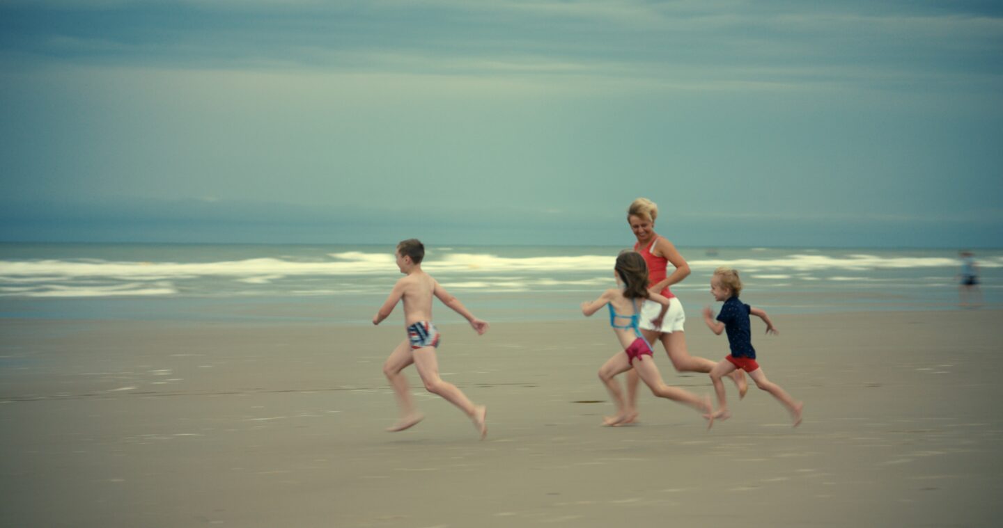 Still-elokuvasta Little Girl. Sashan perhe juoksee hiekkarannalla.