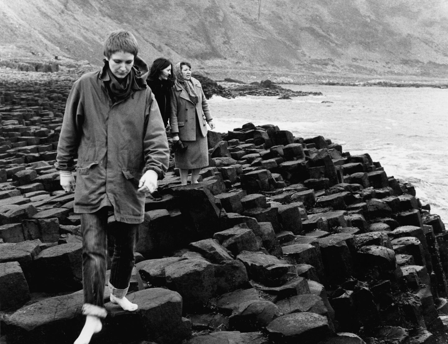 Maeve-elokuvan päähenkilöt kävelevät kivisellä rannalla mustavalkokuvassa.